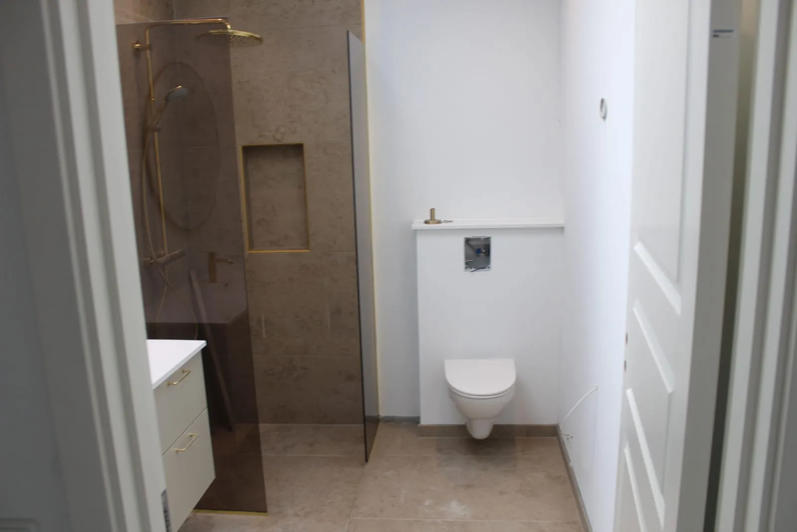 Badeværelse med bruseniche og væghængt toilet med nye fuger