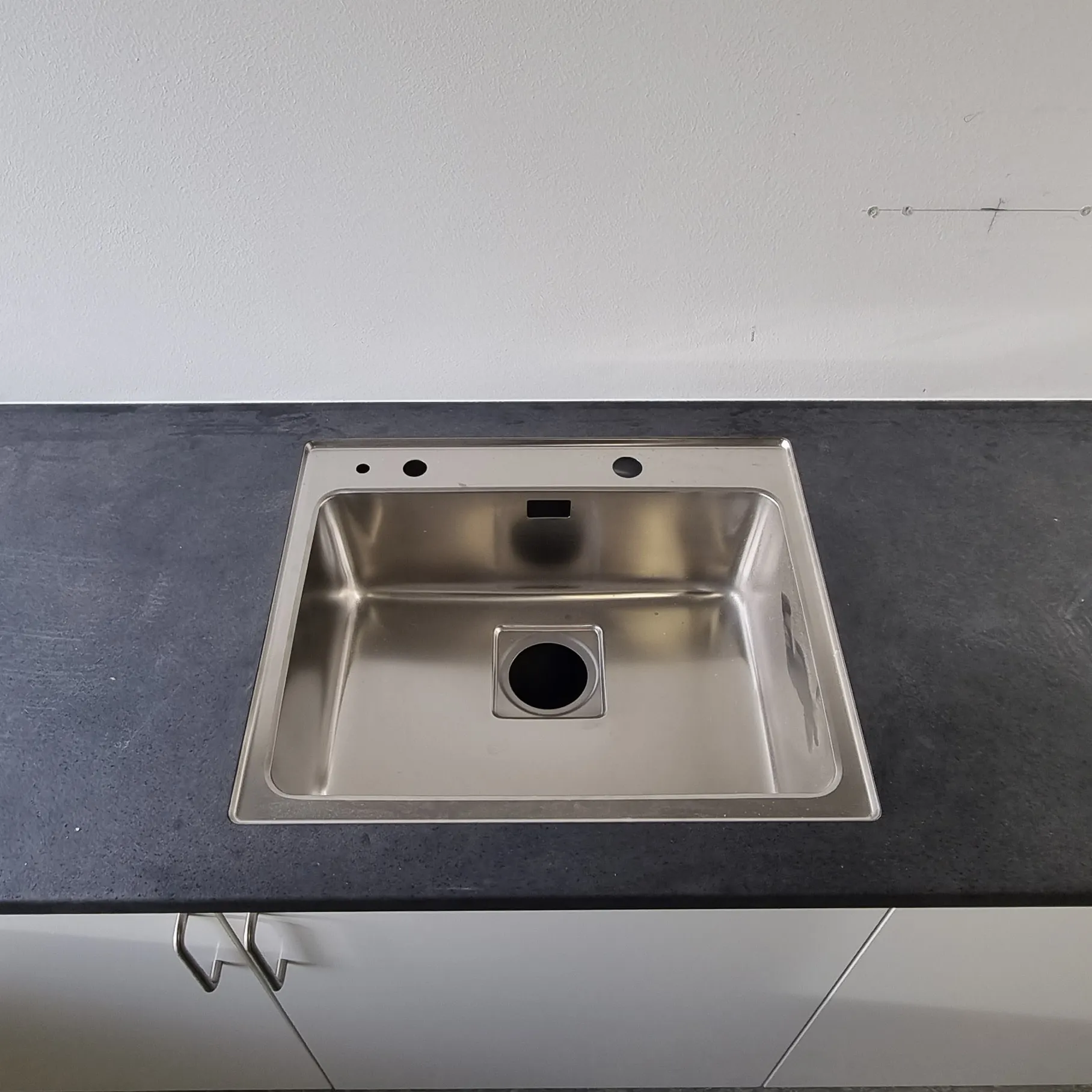 Stålvask i en sort bordplade med en ny fuge mod væggen
