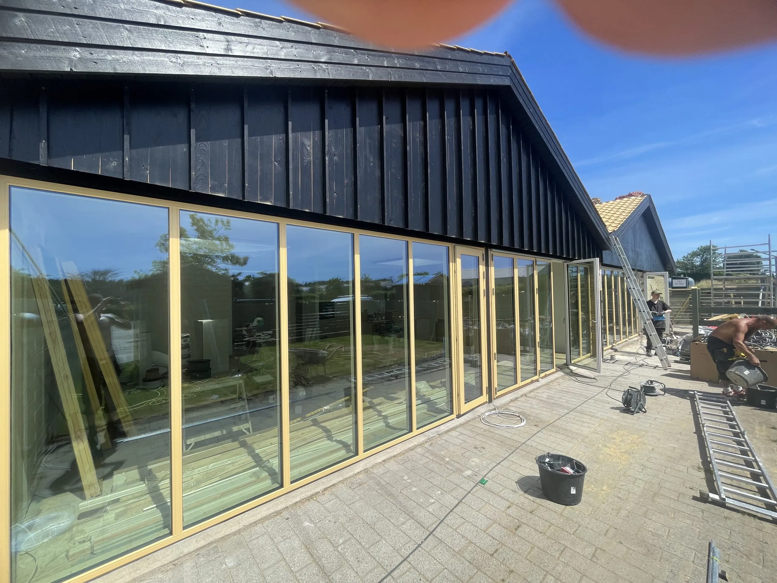 Lang facade med store vinduespartier i gule rammer